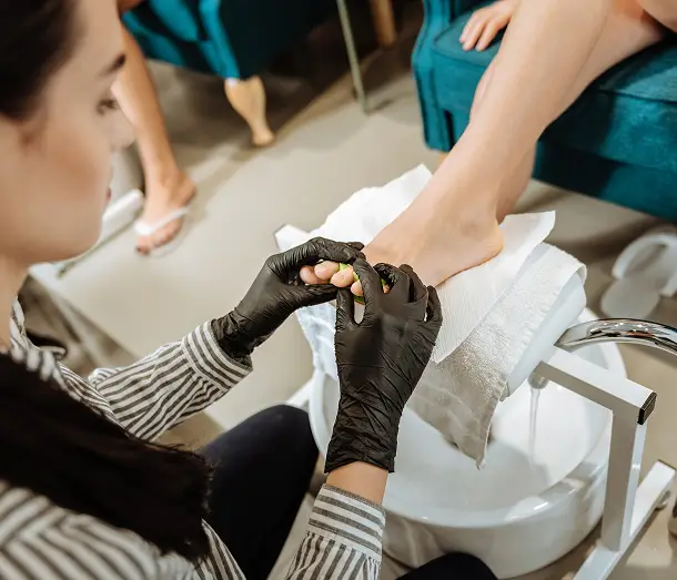 nail specialist performing pedicure to client