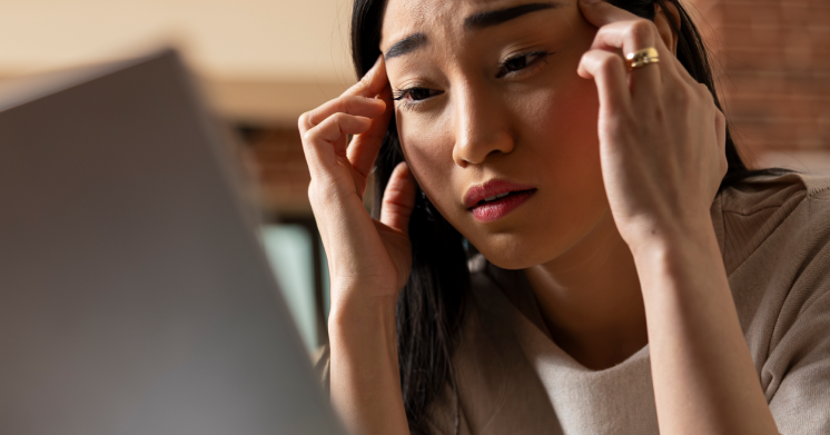 stressed asian woman rubbing her temples 